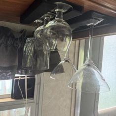 three wine glasses are hanging from the ceiling