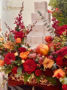 an arrangement of flowers and apples on display