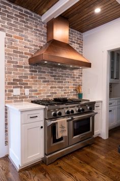 a stove top oven sitting inside of a kitchen next to a wooden floor and white cabinets