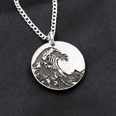 This Titanium necklace is a reinterpretation of the famous painting The Great Wave off Kanagawa by Hokusai. It is a solid titanium disk that we engrave. If you would like to have some custom engraving added to this design (for an extra charge) or something new all together then please message us! All of our jewelry is made by us in our workshop. We have a great team of 4; all of us care deeply that you get exactly what you want and something that you will love for years. Artistic Engraved Silver Necklaces, Artistic Engraved Sterling Silver Necklaces, Artistic Engraved Sterling Silver Necklace, Sterling Silver Etched Round Disc Necklace, Artistic Etched Jewelry For Gifts, Artistic Engraved Round Pendant Necklaces, Artistic Engraved Silver Jewelry, Artistic Engraved Round Pendant Necklace, Silver Stainless Steel Necklaces With Engraving Option