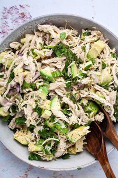 a bowl filled with chicken, broccoli and avocado on top of a table