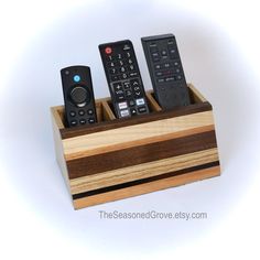 three remote controls sitting in a wooden holder