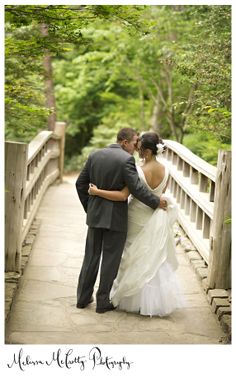 a bride and groom standing on a bridge