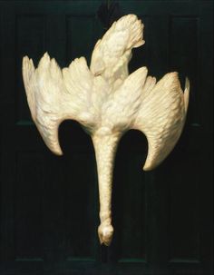 a white bird sculpture hanging from the side of a door