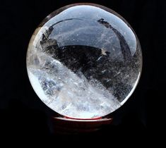 a clear crystal ball sitting on top of a wooden stand in front of a black background