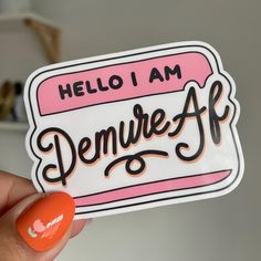 someone holding up a sticker that says hello i am demure af