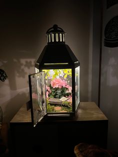 a light that is sitting on top of a wooden table next to a vase with flowers in it