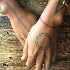 two people with matching tattoos on their arms and fingers, both holding each other's hands