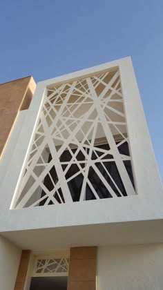 the side of a white building with an open window and geometric design on it's sides