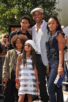 a group of people standing next to each other in front of a crowd on the street