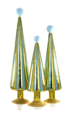 three gold vases with blue and white designs on top of each one in front of a white background