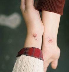 two people with matching tattoos on their arms, both holding each other's hands