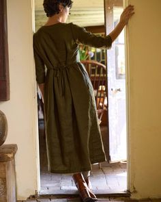 a woman in a green dress is standing at the door and looking into the room