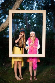 two women standing next to each other in front of a photo frame