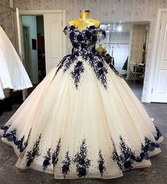 a white and blue ball gown on display in a room with mannequins