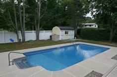 an empty swimming pool surrounded by trees and fenced in area with white picket fence