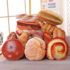 many different types of breads and pastries on a white bench in front of a window