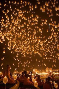 people are sitting on the ground and floating lanterns in the sky with words happy birthday