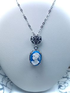 Simulated Blue & White Portrait Cameo Sterling Silver Pendant NecklaceEdward Design#P70 Introducing the Edward Design P70 Blue Cameo Portrait Pendant! This exquisite pendant is sure to make a lasting impression with its timeless, romantic design. Crafted from sterling silver and encrusted with a captivating 14mm by 10mm simulated Blue Cameo, you won't be able to resist the vintage Victorian style created by this remarkable piece of jewelry.The filigree detailing of the pendant and its bail adds Blue Cameo Jewelry For Formal Occasions, Formal Blue Cameo Jewelry, Blue Cameo Necklace For Formal Occasions, Edwardian Necklace, White Portrait, Filigree Necklaces, Romantic Design, Cameo Pendant, Sterling Silver Filigree