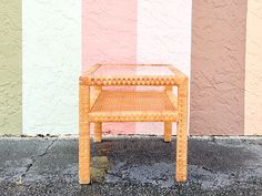 a small wicker table sitting in front of a multicolored wall with stripes on it