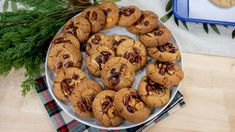 a plate full of cookies with nuts on it next to a cookie tin and christmas greenery