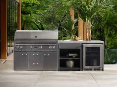 an outdoor kitchen with stainless steel appliances and grilling area next to pool in tropical setting