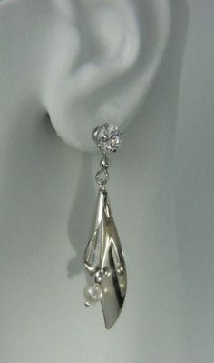 "This pair of solid sterling silver dangle Calla Lily fresh water pearl Earring Jackets have a smooth shiny texture. The Earring Jackets are 45mm (1 and 3/4\") long and 12 mm (1/2\") wide at it's widest. These jackets will nicely enhance your diamond or gemstone stud earrings. The diamond stud earrings shown here (one carat each) are for illustration purposes only and are NOT INCLUDED with earring jacket purchase. The holes in these earring jackets are large enough to accommodate any post earrin Silver Clip-on Pearl Jewelry, Silver Clip-on Pearl Earrings For Evening, Silver Pearl Clip-on Jewelry, Silver Pearl Earrings With Pearl Pendant, Evening Sterling Silver Pearl Earrings With Pendant, Silver Drop Pearl Earrings In Sterling Silver, Silver Drop Earrings With Pearl Detail, Sterling Silver Clip-on Drop Pearl Earrings, Sterling Silver Clip-on Pearl Drop Earrings