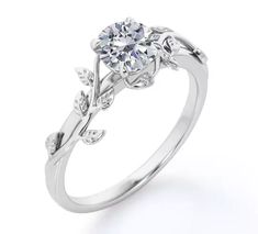 a white gold engagement ring with leaves on the band and a round diamond center stone