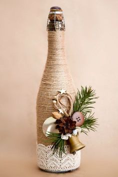 a wine bottle decorated with pine cones, bells and other decorations sits on a table