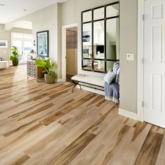 a living room filled with furniture and a mirror on top of a wooden floor next to a doorway