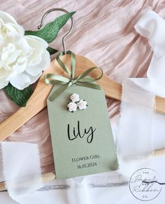 a flower girl hanger with flowers on it and a tag attached to the hanger