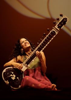 a woman sitting on the ground holding an instrument