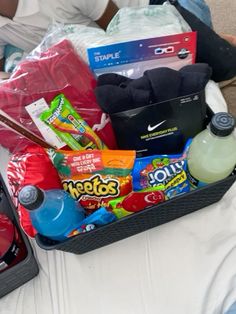 a basket filled with snacks and drinks on top of a bed