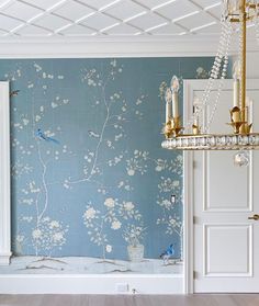 a room with blue and white wallpaper, gold chandelier and two doors