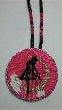 a pink and black beaded necklace with a silhouette of a woman holding a surfboard