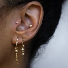 a close up of a person's ear wearing gold earrings with stars on them