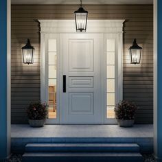 the front door is lit up with two lights on each side and flowers in pots at the bottom