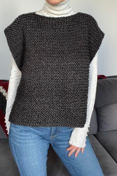 a woman standing in front of a couch wearing a black and white knitted sweater