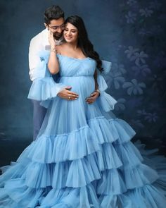 a pregnant woman in a blue gown poses with her husband