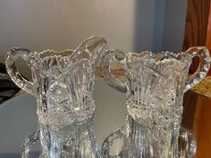 two clear glass pitchers sitting on top of a table