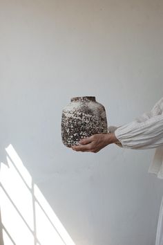 a person holding a vase in their hand with sunlight coming through the window behind them