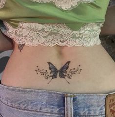 a woman's stomach with a butterfly tattoo on her lower back and the bottom part of her abdomen