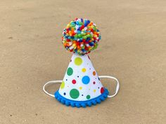 "A MINI party hat made out of colorful polkadot fabric and trimmed with mini bright ocean blue pom poms on bottom and a speckled yarn pom pom on the top.  Attached to a 1/8\" elastic- to be worn comfortably like a headband.  Diameter of hat is 3\", and height 4\". OPTIONS: -Bottom Pom Pom trim color  -Number- with or without  * please provide desired number/outline color in comments section  DOGS:  If you are purchasing for a dog, please provide entire head circumference measurement- start at to Adjustable Multicolor Hat For Birthday, Fun Multicolor Birthday Hats, Fun Hats For Birthday And Carnival, Playful Hats For Birthday And Carnival, Fun Costume Hats And Headpieces For Birthday Carnival, Fun Carnival Birthday Hats, Fun Birthday Carnival Hats, Playful Multicolor Birthday Party Supplies, Playful Mini Hats For Birthday Carnival