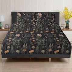 a bed covered in a black floral comforter