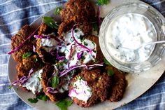 a white plate topped with meat patties covered in sour cream and garnished with cilantro