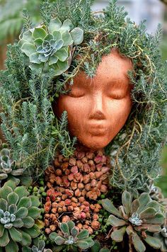 a head made out of plants and succulents in the shape of a woman's face