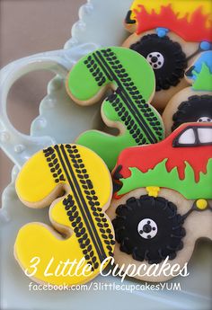 decorated cookies in the shape of cars and trucks are on a plate with a mug