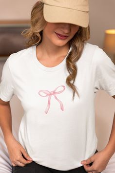 * Add a touch of sweetness to your wardrobe with this adorable pink bow t-shirt! This women's t-shirt features a charming pink bow printed design that is both cute and stylish. Made from high-quality materials, this top is perfect for adding a pop of color to any outfit. Whether you're heading out for a casual day out or just want to add a fun element to your look, this sweet pink bow t-shirt is sure to become a favorite in your collection. * Available in Multiple Sizes: Our T-Shirt comes in a r Casual Summer T-shirt With Pink Bow, Casual Crew Neck T-shirt With Bow Print, Casual Short Sleeve T-shirt With Pink Bow, Cute Bow T-shirt For Spring, Feminine Cotton Short Sleeve T-shirt, Cute Pink T-shirt With Bow, Feminine Pink Crew Neck T-shirt, Feminine Ribbon Tops For Spring, Feminine Tops With Ribbon For Spring