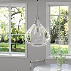 a dining room table with two chairs and a vase on the table in front of three windows