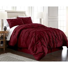 a bed in a room with a red comforter and pillows